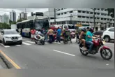 Pedestres prestam os primeiros socorros a motociclista após acidente com ônibus
