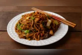 Yakissoba caseiro preparado com espaguete, carne, legumes e molho shoyu é uma opção prática para o almoço ou jantar.