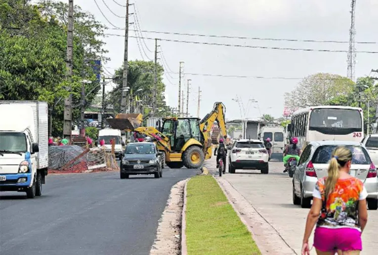 Pedestres caminham em meio a obra não concluída. 
