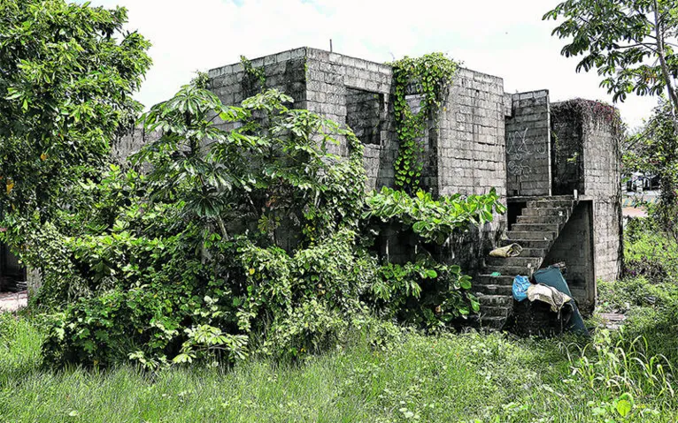 Conjunto segue inacabado, enquanto famílias desalojadas em 2008 têm de esperar. Mato e sujeira já tomam conta dos prédios no local. 