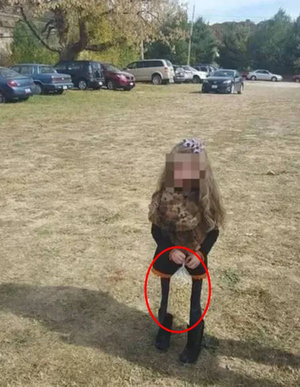Olhando atentamente dá para ver um saco de pipocas entre as pernas da menina. 