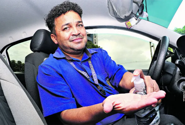 O taxista Odair Aguiar usa álcool em gel para higienizar seu carro

