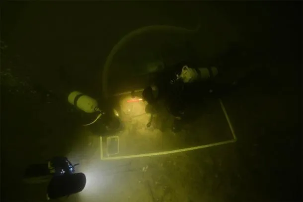 Arqueólogos subaquáticos examinando os artefatos no Lago Asveja, Lituânia