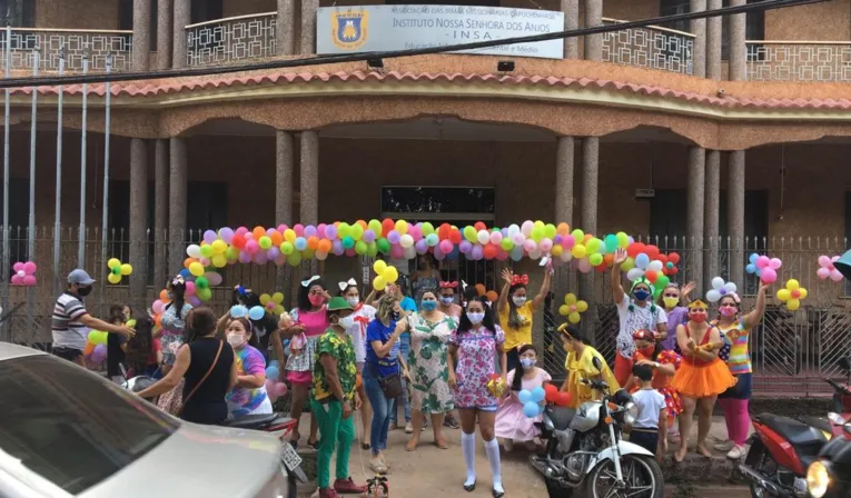 Profissionais em frente a escola, com a alegria garantida para animar os estudantes que passavam em seus transportes. 