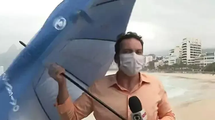 Repórter luta para não perder o guarda-chuva na ventania
