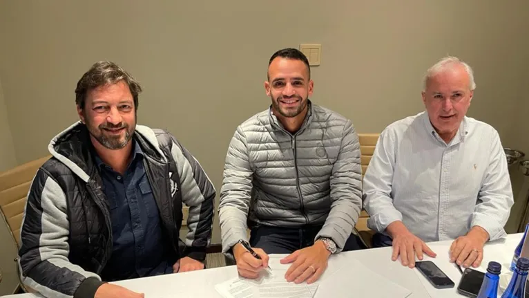Renato Augusto no momento em que está assinando o contrato.