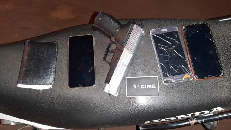 Celulares e imitação de pistola apreendidos com os acusados 