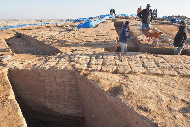 Arqueólogos escavando as largas paredes do edifício de armazenamento descoberto no local
