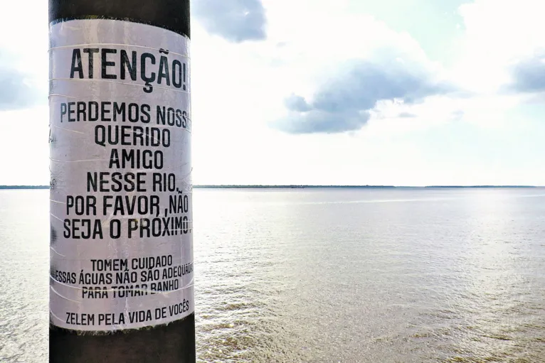 Familiares de um jovem que morreu afogado preparam cartazes para alertar populares sobre os perigos de cair no rio