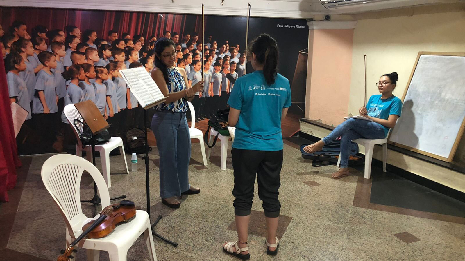 Alunas do Programa Vele Música Belém tomam aula de violino.