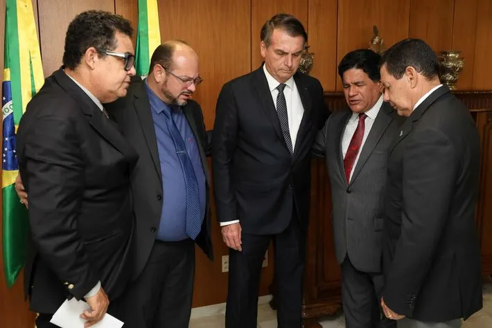 Presidente Bolsonaro e Mourão, orando com os pastores Gilmar dos Santos, Pastor Airton Moura Correia e Pastor José do Nascimento Pires Sampaio Junior.