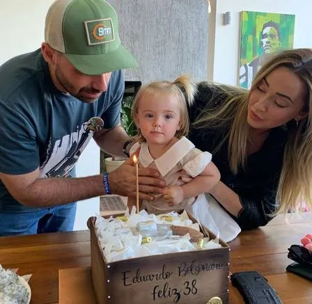 Eduardo e Heloísa Bolsonaro, com a filha, ao lado do bolo com temática de revólver.