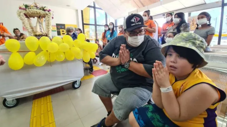 Criança usuária do CIIR junta as mãos em oração à passagem da imagem da Virgem de Nazaré no mini Círio da instituição