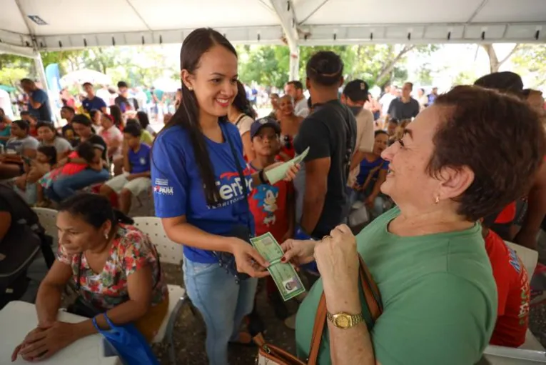 Moradora recebee a nova RG das mãos de servidora estadual e sorri com gratidão