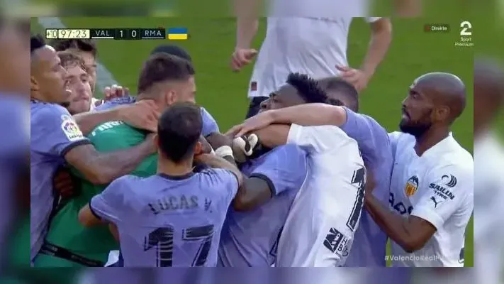 Vinícius Júnior é seguro pelo pescoço por um adversário em meio à confusão entre os jogadores de Real e Valencia, no jogo do último domingo (21).