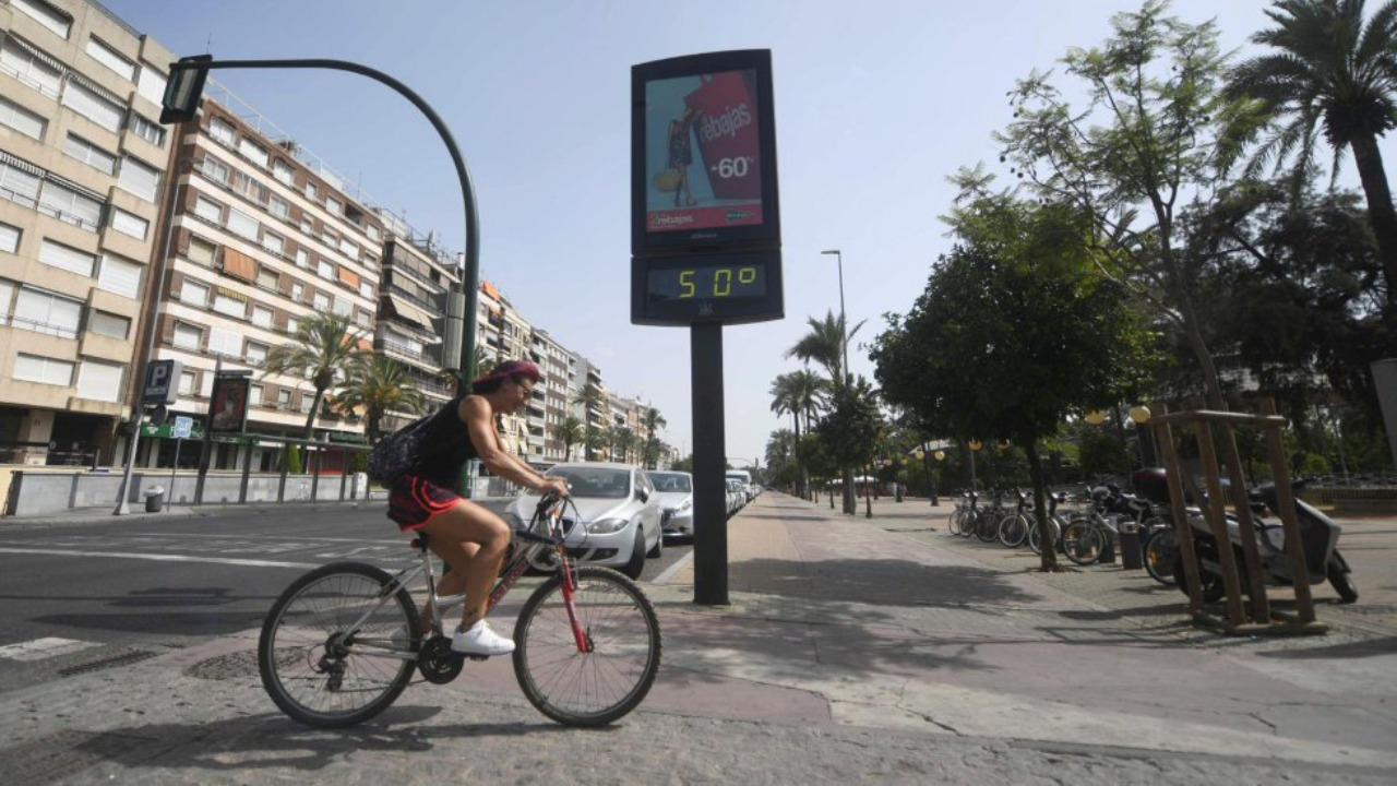 Ciclista passa em frente a um termômetro que marca 50ºC em Córdoba