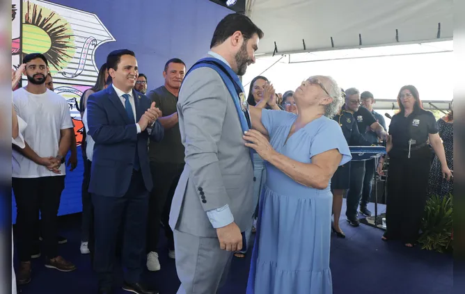 Dona Benedita, antiga moradora de Outeiro, coloca a faixa no prefeito, Igor Normando.