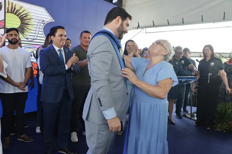 Dona Benedita, antiga moradora de Outeiro, coloca a faixa no prefeito, Igor Normando.