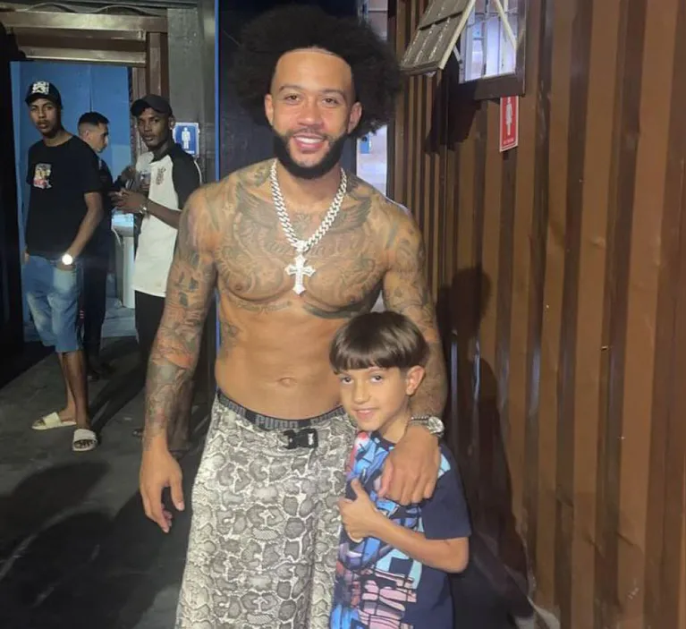Depay posa ao lado de criança durante visita à comunidade no ABC Paulista.
