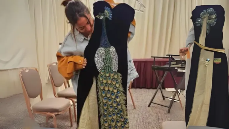 O famigerado vestido preto de pavão roxo que deixou o rei debaixo do banho após abraço