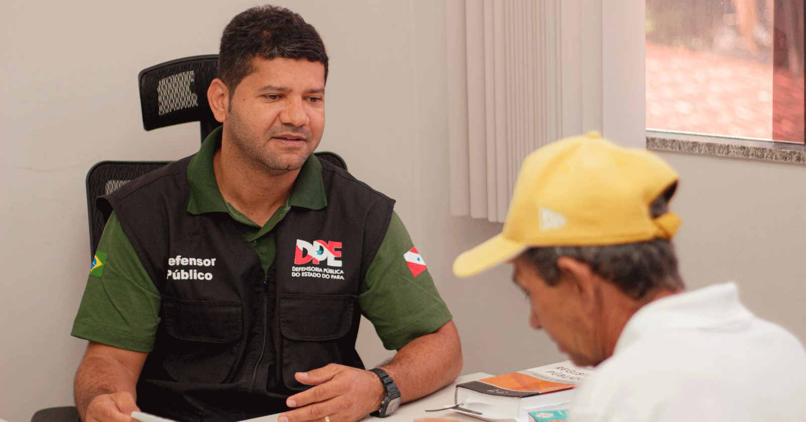 Agente da Defensoria Pública orienta cidadão sobre serviços jurídicos.