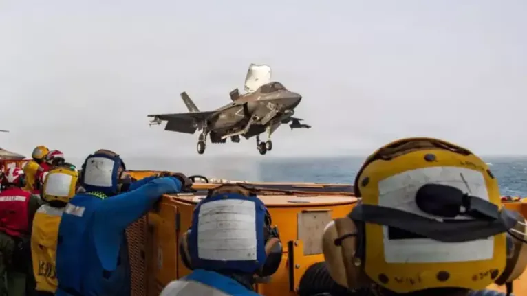Militares americanos a bordo do navio de assalto anfíbio USS Boxer observam um caça dos Estados Unidos durante operação militar.
