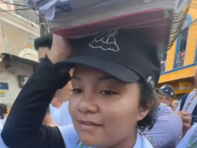 Estudante leva cadernos sobre a cabeça como forma de agradecer pela conquista ou aprovação nos estudos.