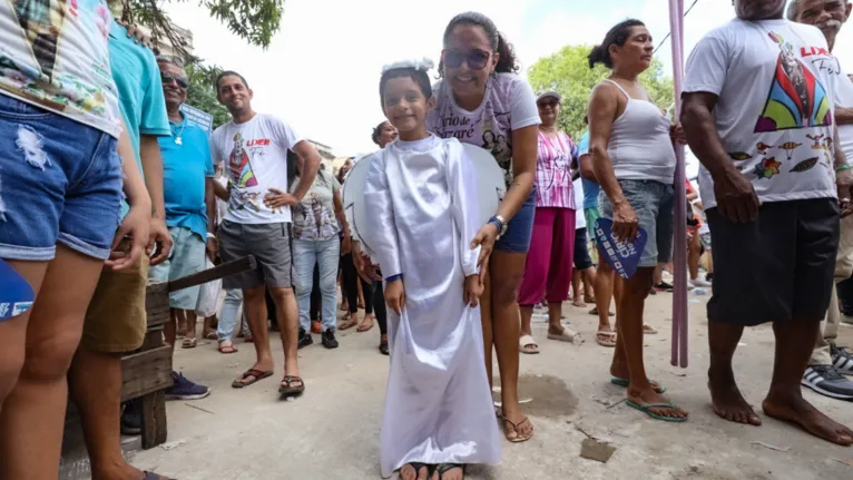 Criança vestida de anjo participa do Círio ao lado da mãe em cumprimento a uma promessa feita pela família.