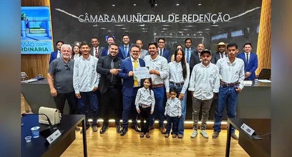 Weliton Ribeiro Gomes, o Timbó, ladeado por autoridades durante o recebimento da Moção de Aplausos na Câmara Municipal.